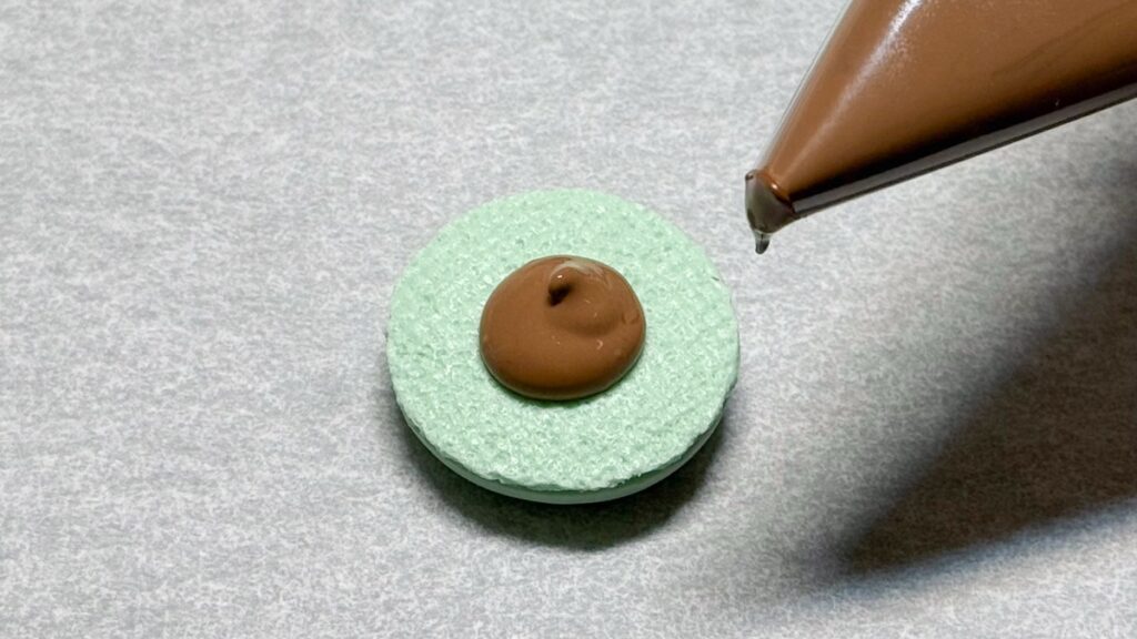 マカロンにチョコレートフィリングを絞る